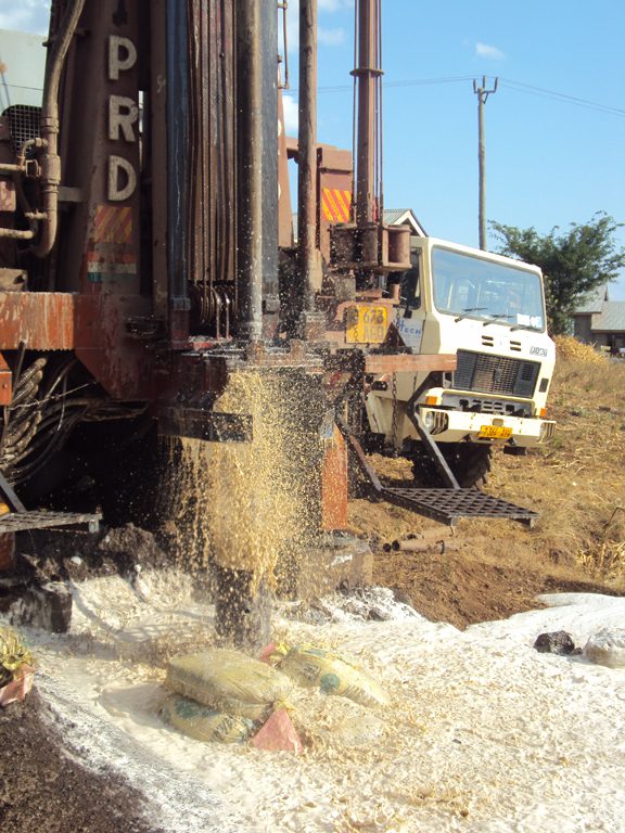 A truck is driving down the road with a pile of dirt.