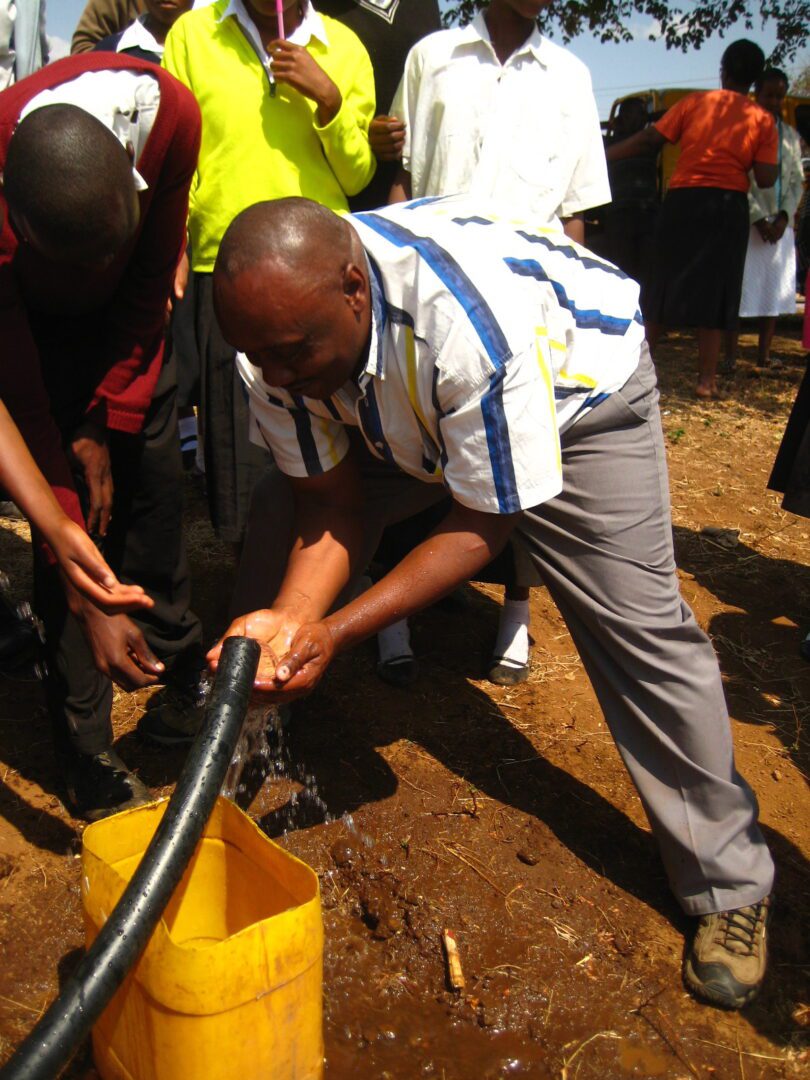 A man is using a hose to fill up a hole.