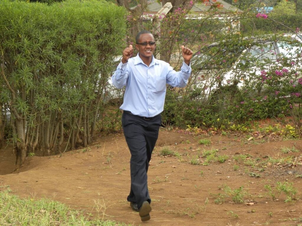 A man is walking in the dirt with his hands up.