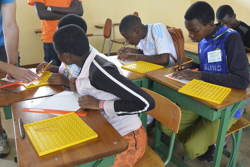 A group of young people sitting at desks working on laptops.