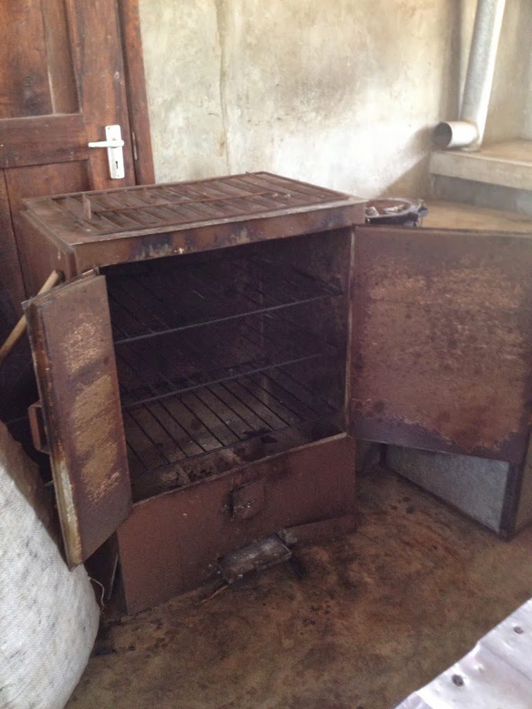 A large wooden oven in the middle of an old kitchen.