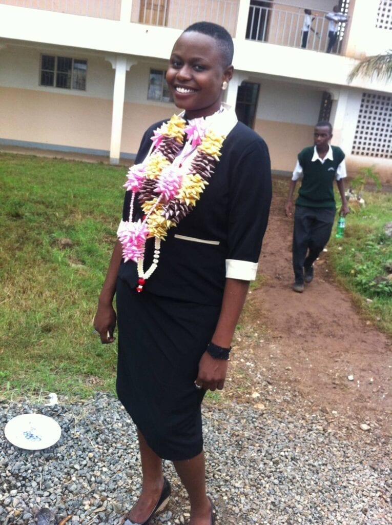 A woman in black dress standing on dirt path.