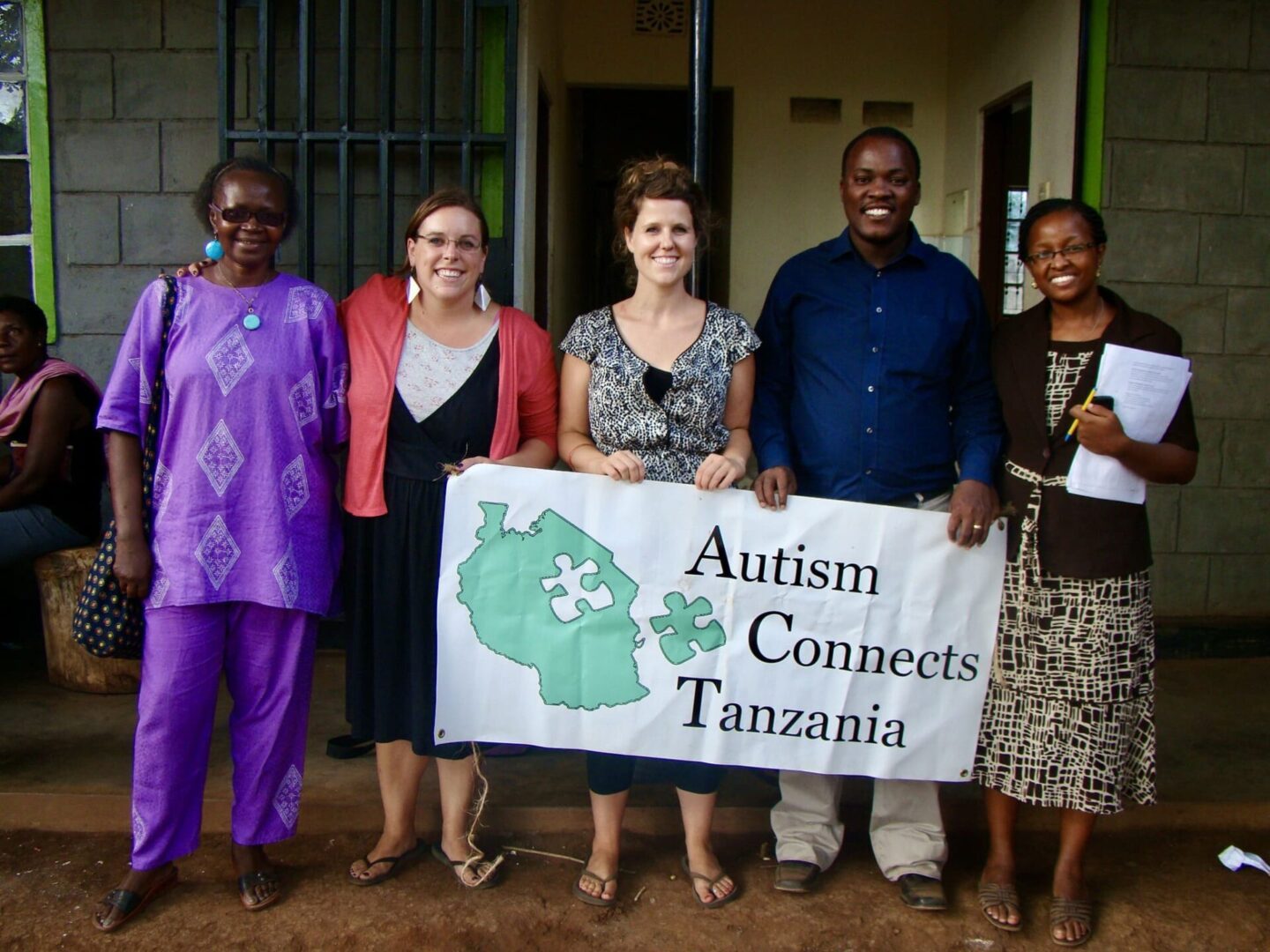 A group of people standing next to each other holding an autism connects tanzania banner.