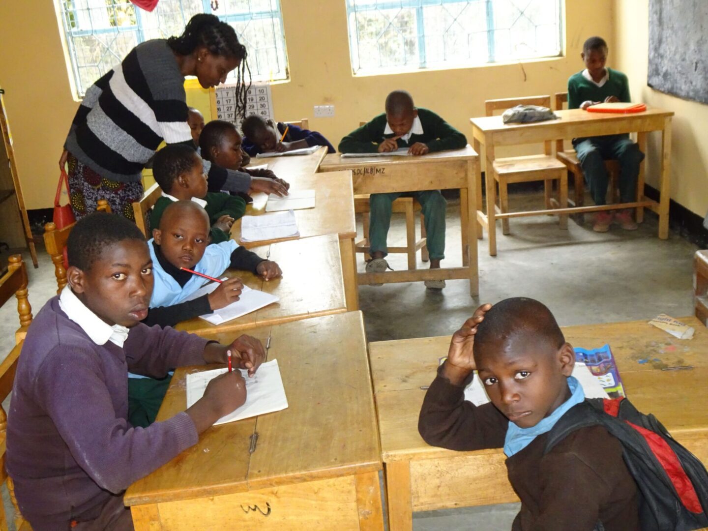 A group of children sitting at desks in front of a man.