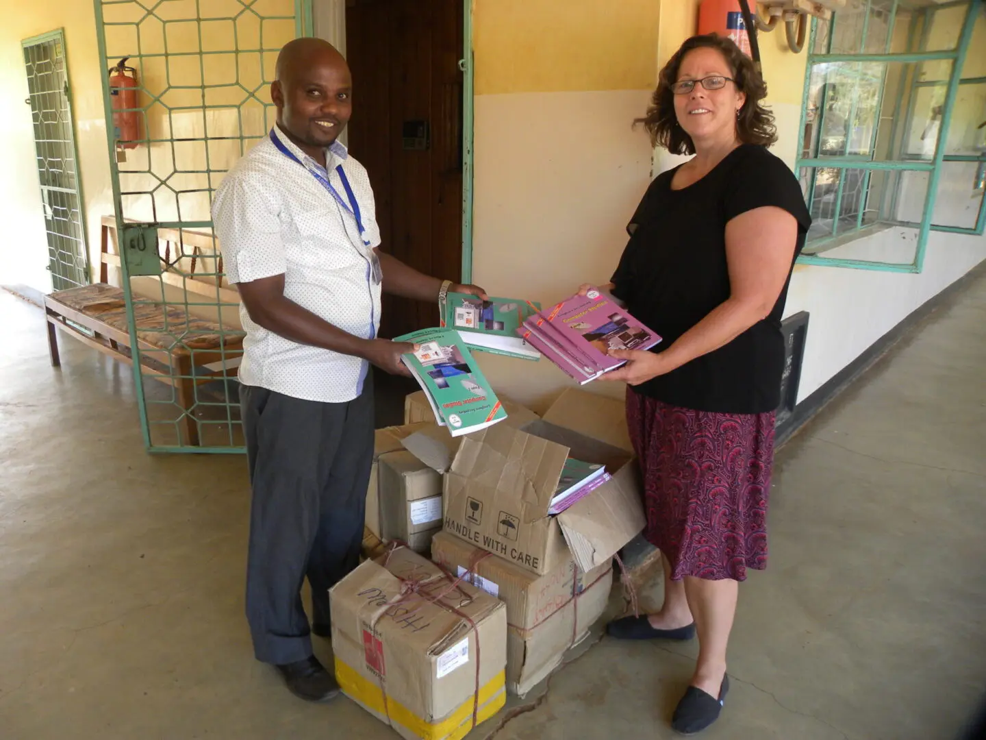 A man and woman standing next to boxes of books.