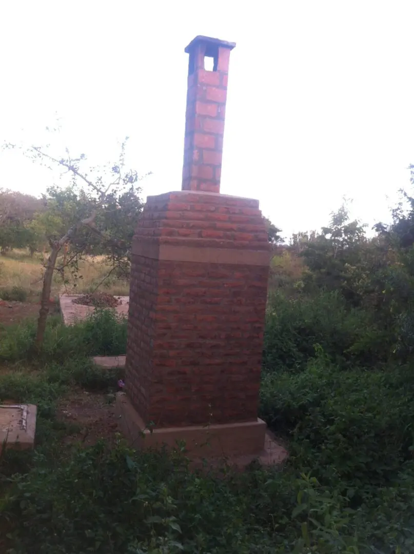 A brick monument in the middle of a field.