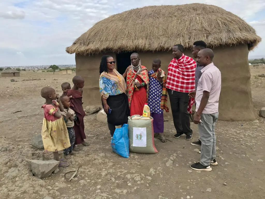 A group of people standing around in front of a hut.