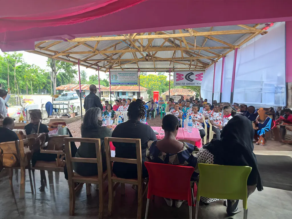 Group of people sitting at tables under a roof.