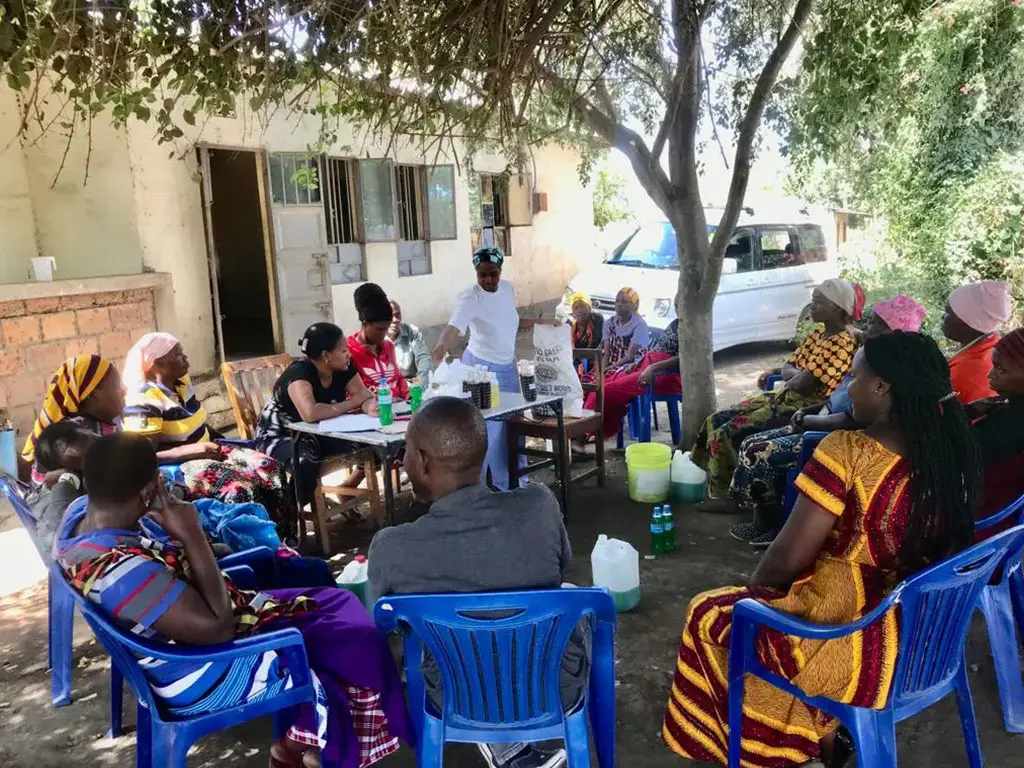 Group of women gathered under a tree.