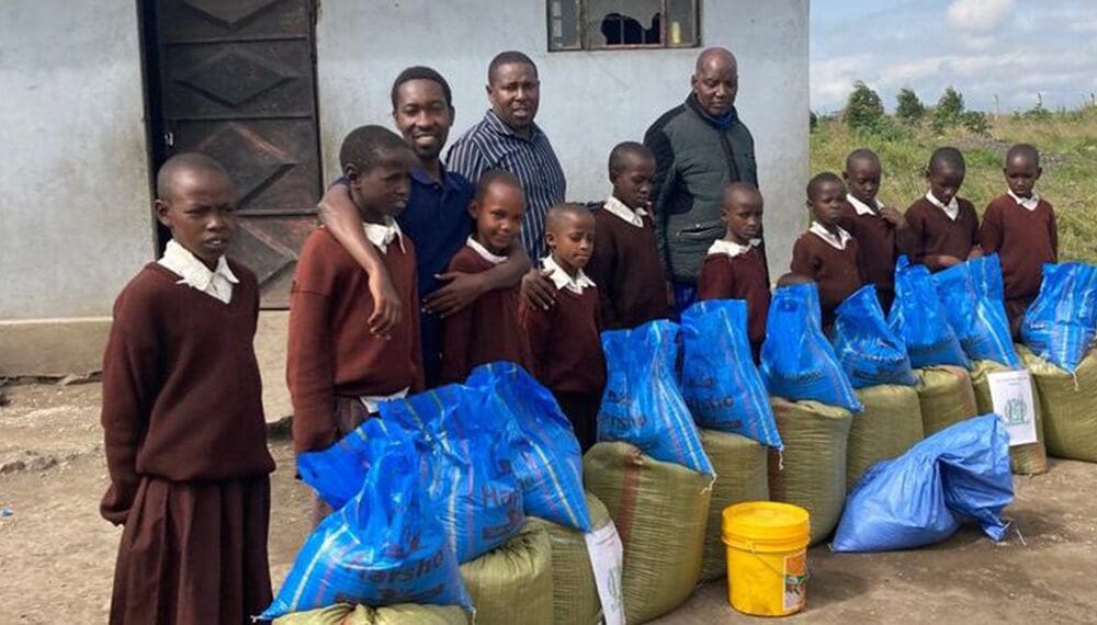 Children in uniforms with donated supplies outside.