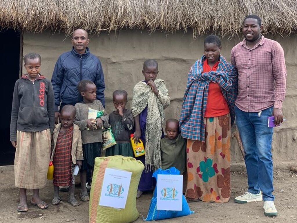 Group of people with food supplies outside hut.