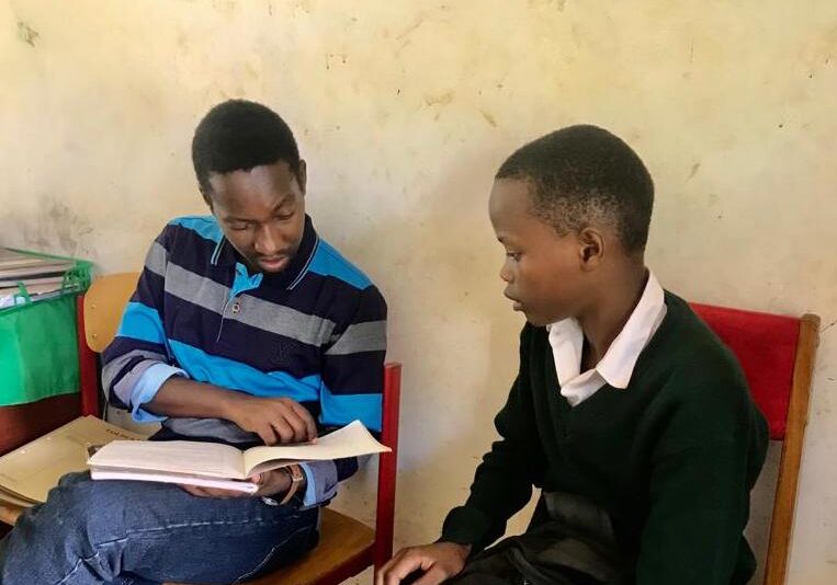 Two boys are sitting and reading together.