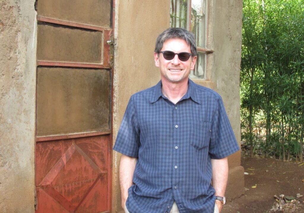 A man standing in front of a building wearing sunglasses.